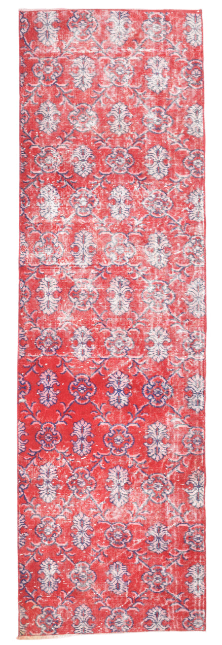 Red patterned rug with white floral design on a plain background