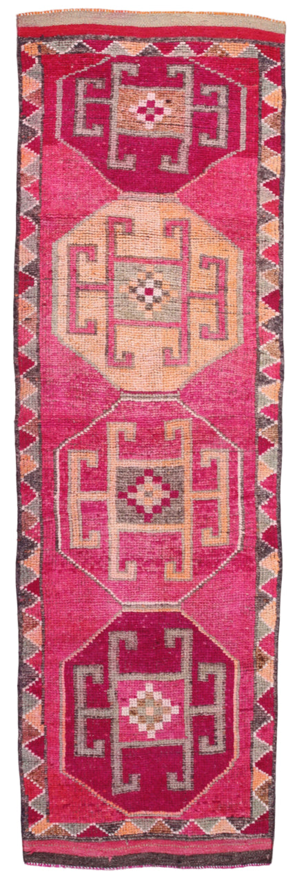 Pink runner rug with geometric patterns on a plain background
