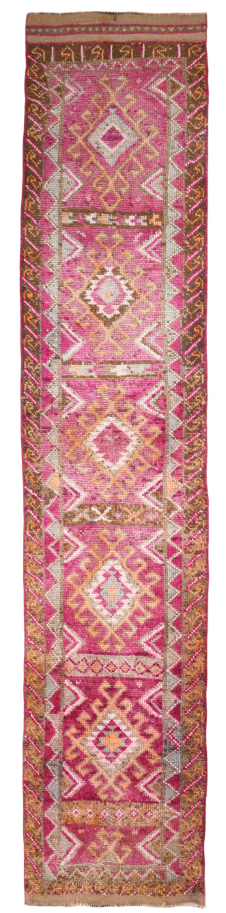Long, narrow pink and red patterned rug with geometric designs.