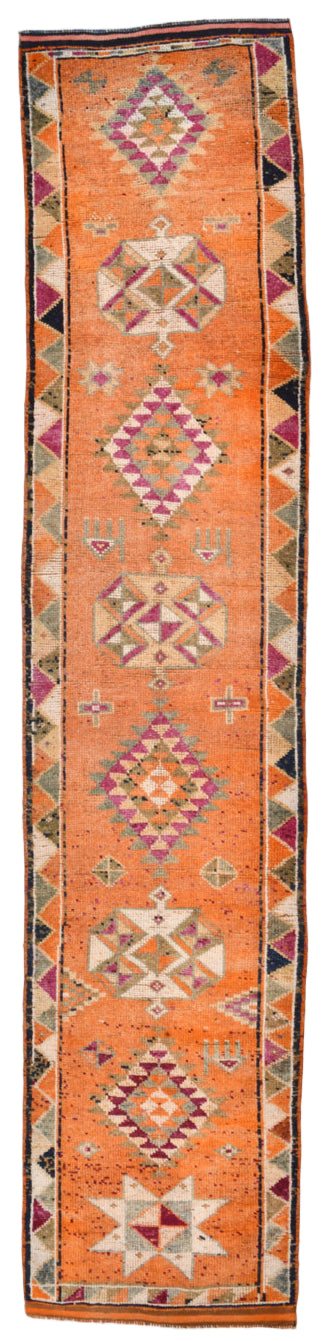 Long, narrow rug with geometric pattern on an orange background