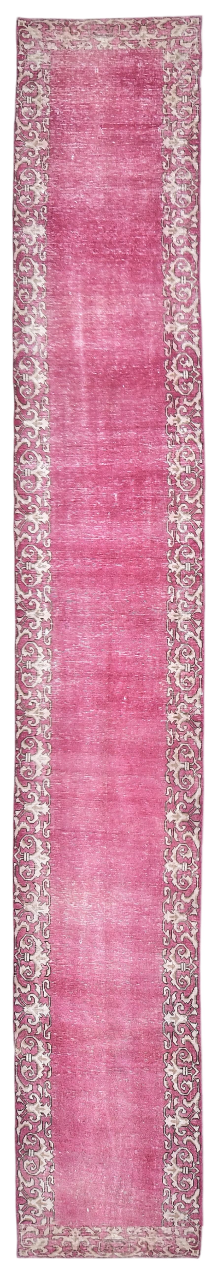Pink runner rug with intricate patterns on a plain background
