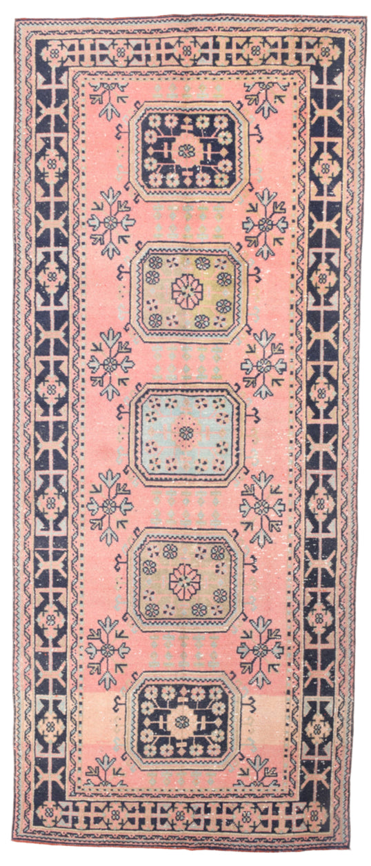 Decorative rug with a pink background and geometric pattern