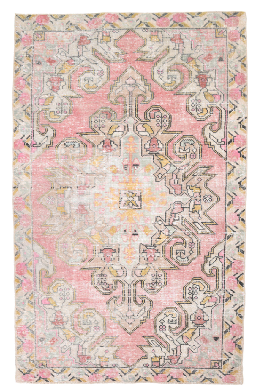 Decorative pink rug with intricate patterns on a plain background