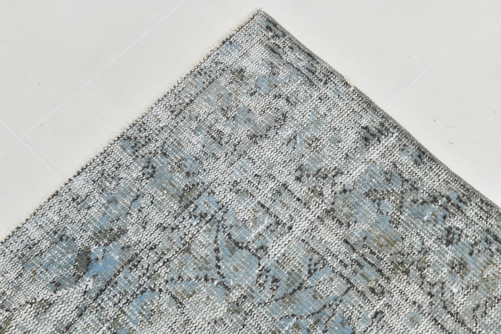 Close-up of a textured blue and gray rug on a light gray background