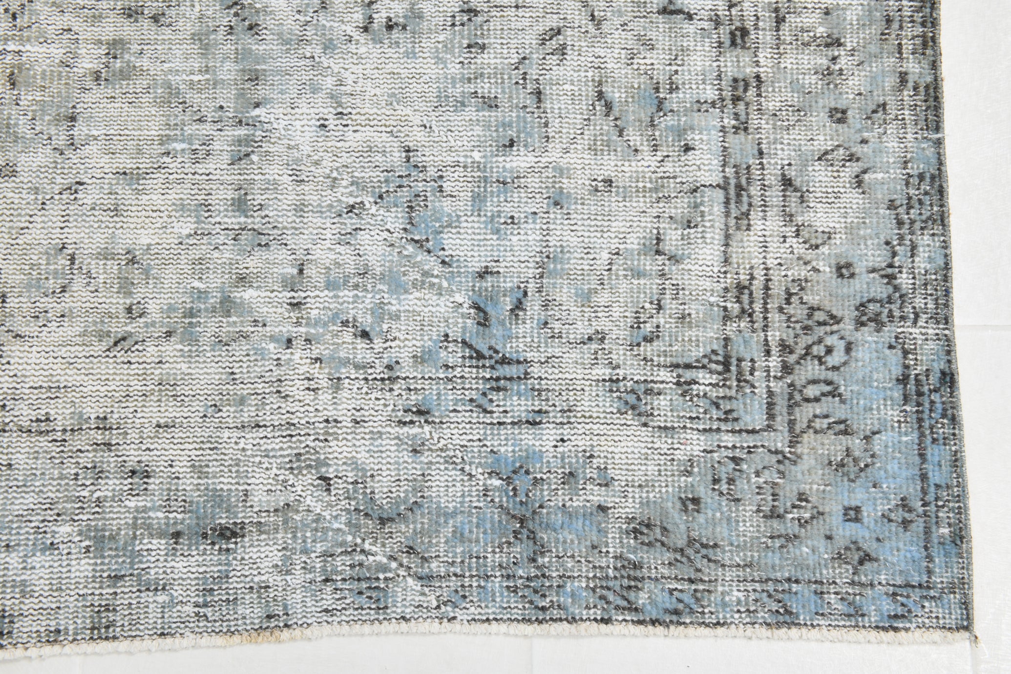 Textured blue and gray rug corner on a white background