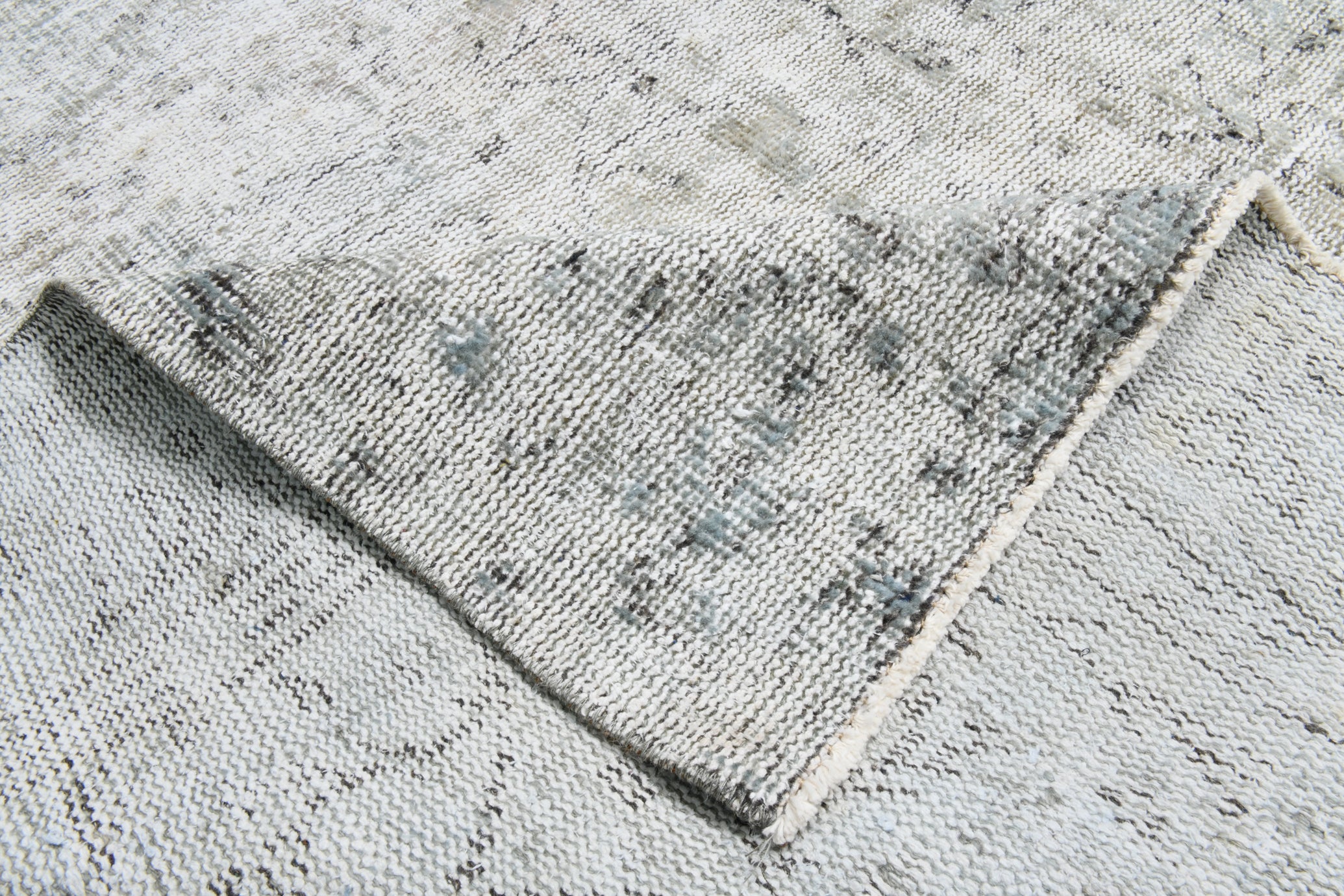 Textured gray rug with a diamond pattern on a concrete floor.