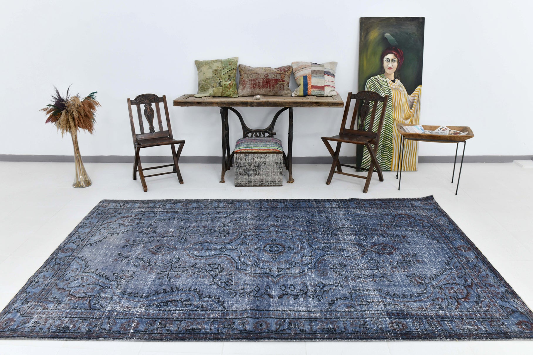 Blue patterned rug in a room with chairs, table, and artwork.